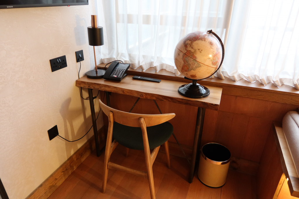 treehouse hotel london studio suite desk with bin, globe, chair, lamp and phone