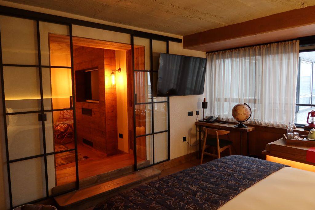treehouse hotel london studio suite bedroom with glass sliding door and TV on wall